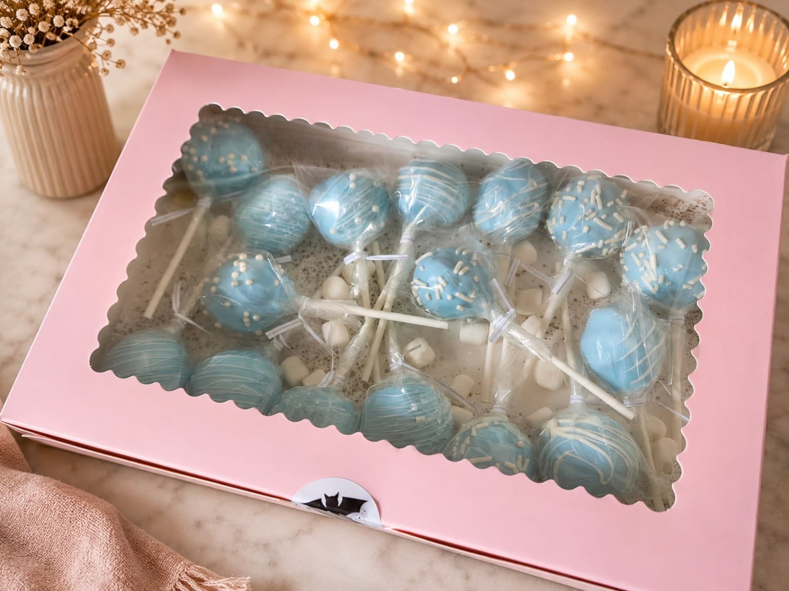 Pink gift box filled with blue and white Sugar Spell cake pops on sticks